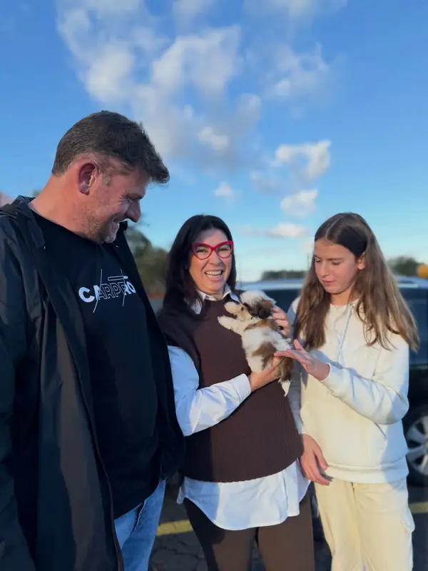 The Harpson family beside their car on the day they collected Milo, a brown and white Shih Tzu puppy